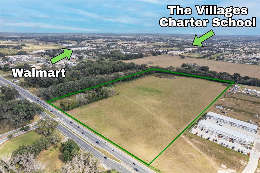 An aerial view shows a large, vacant grassy lot bordered by a road and trees — 11425 N US HIGHWAY 301, OXFORD, FL