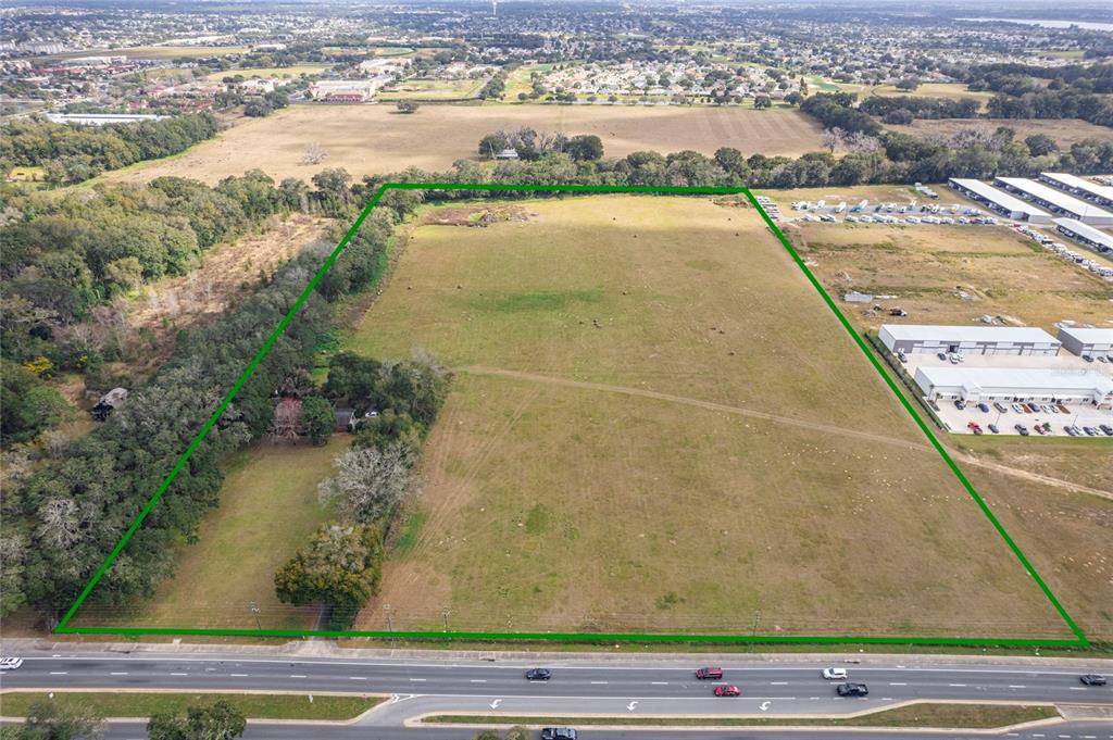 An aerial view shows a large, rectangular grassy lot bordered by trees and a highway — 11425 N US HIGHWAY 301, OXFORD, FL
