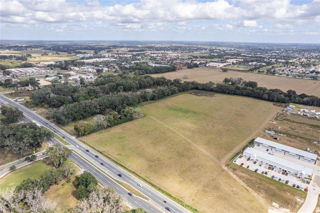 An aerial view shows a large, vacant grassy lot adjacent to a highway and buildings — 11425 N US HIGHWAY 301, OXFORD, FL