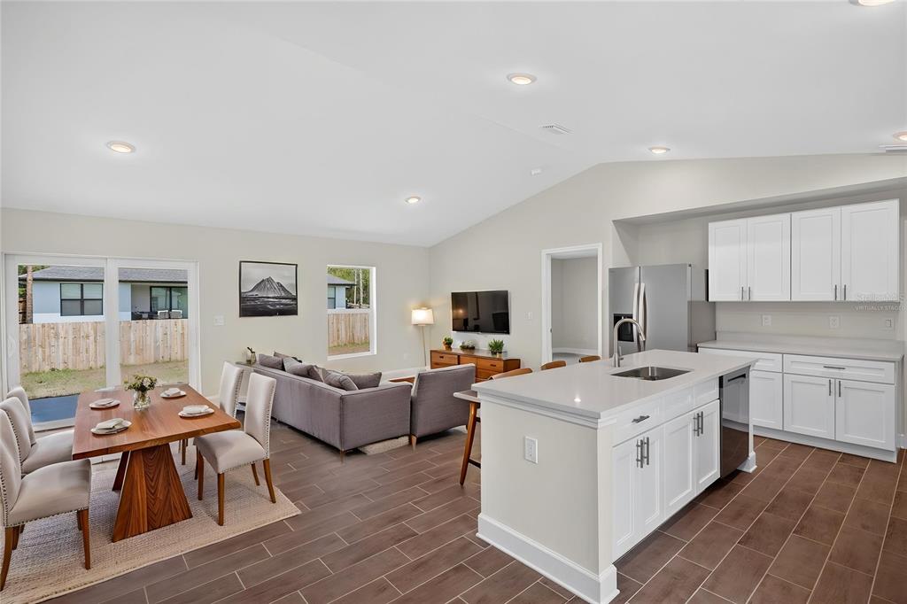 An open-concept kitchen, dining area, and living room featuring white cabinetry and tile flooring — 3254 PLYMOUTH STREET, PORT CHARLOTTE, FL