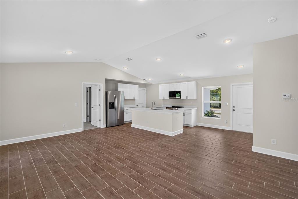 An open-concept kitchen with white cabinets, a central island, and wood-look tile flooring — 3254 PLYMOUTH STREET, PORT CHARLOTTE, FL