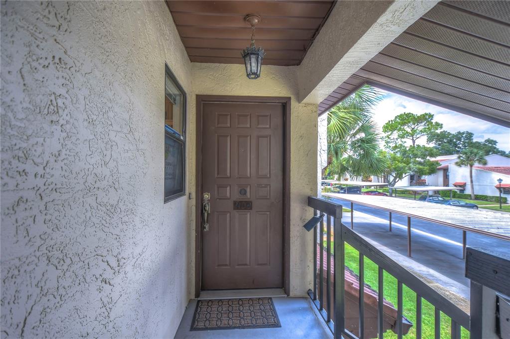 A brown front door with a small porch and a view of a parking area — 3505 TARPON WOODS BOULEVARD UNIT Q409, PALM HARBOR, FL