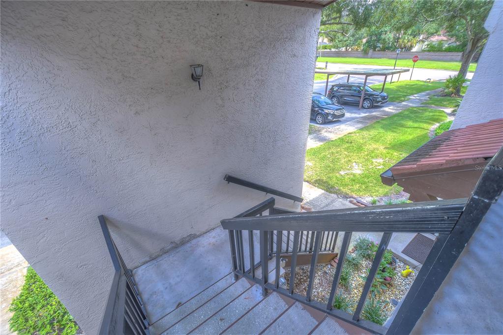 An outdoor staircase with dark railings leads down from a building to a parking area — 3505 TARPON WOODS BOULEVARD UNIT Q409, PALM HARBOR, FL