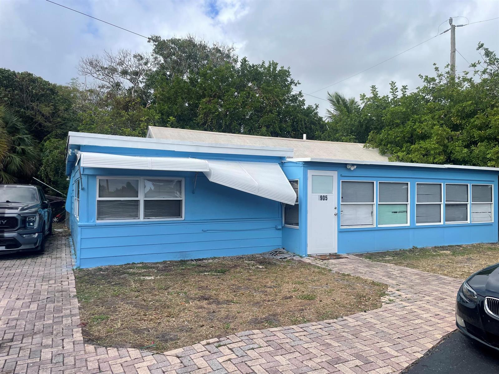 A bright blue single-story house features a white metal awning and a paved driveway — 1905 Florida Street, FL 33460, FL