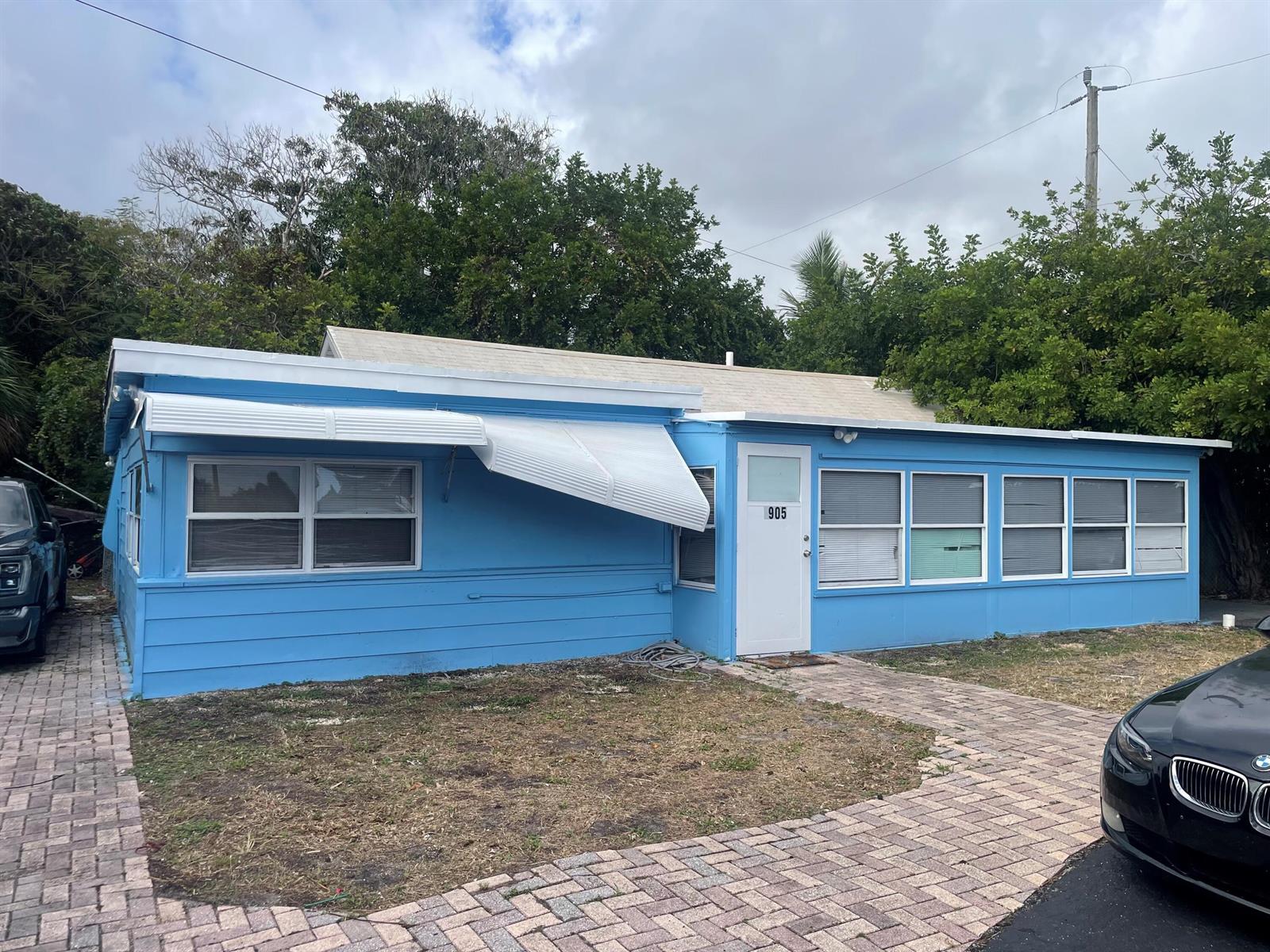 A blue, single-story house with a white metal awning and a brick paver driveway — 1905 Florida Street, FL 33460, FL