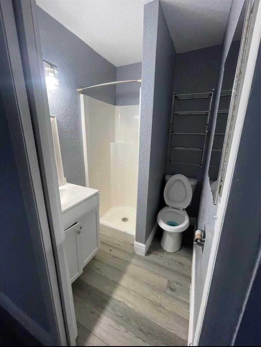 A small bathroom features a white vanity, a corner shower, and a toilet against gray walls — 1905 Florida Street, FL 33460, FL