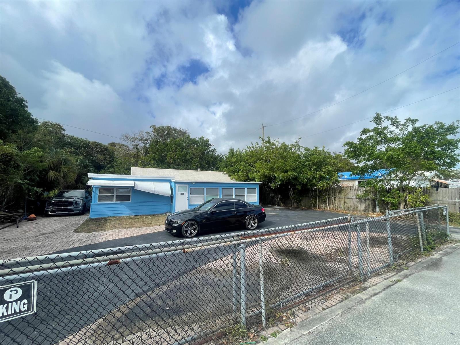 A blue house with a black car parked in the driveway behind a chain-link fence — 1905 Florida Street, FL 33460, FL