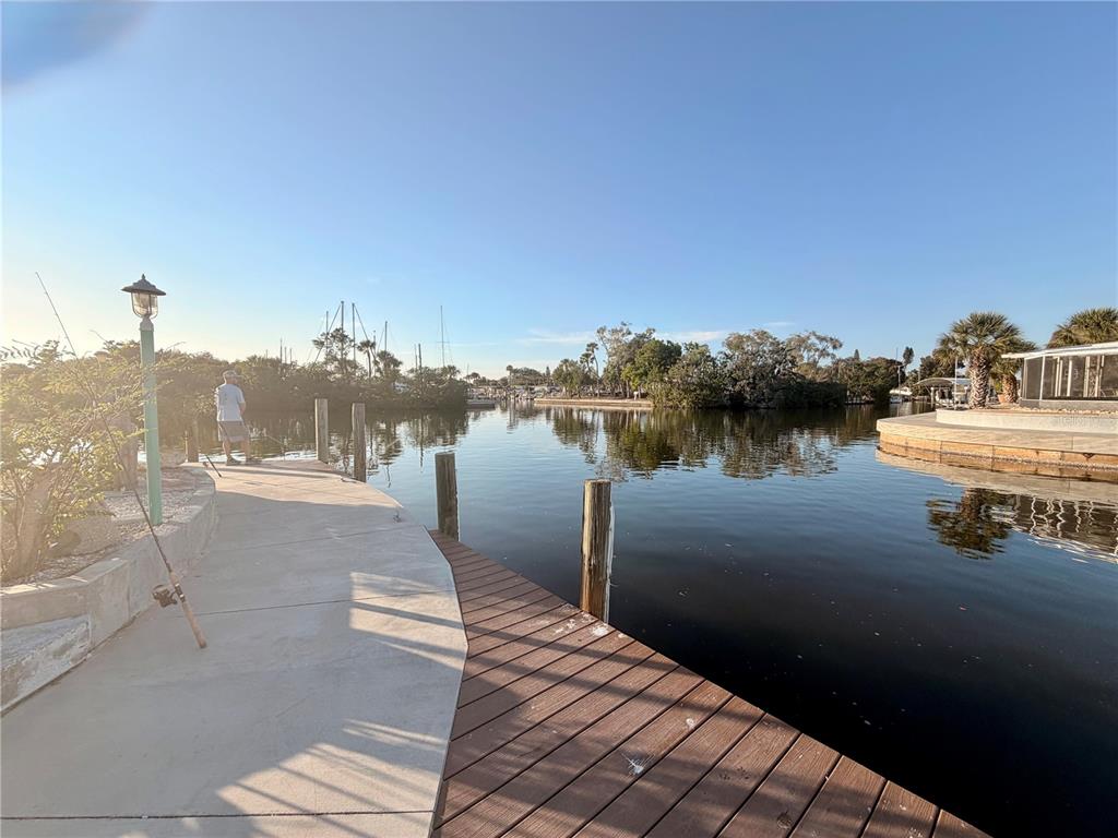 A person fishes from a concrete and wooden dock overlooking a calm canal — 2208 PENNSYLVANIA AVENUE, BRADENTON, FL