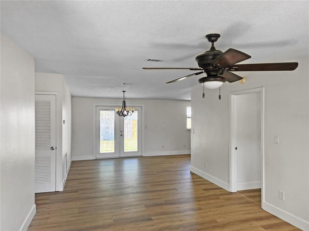 An open living area features light-colored walls, wood-look flooring, a ceiling fan, and French doors — 430 SANTIAGO AVENUE, ORLANDO, FL