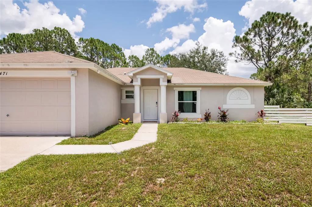 A single-story house with a beige stucco exterior, a garage, and a front walkway — 2471 QUINCY AVENUE SE, PALM BAY, FL