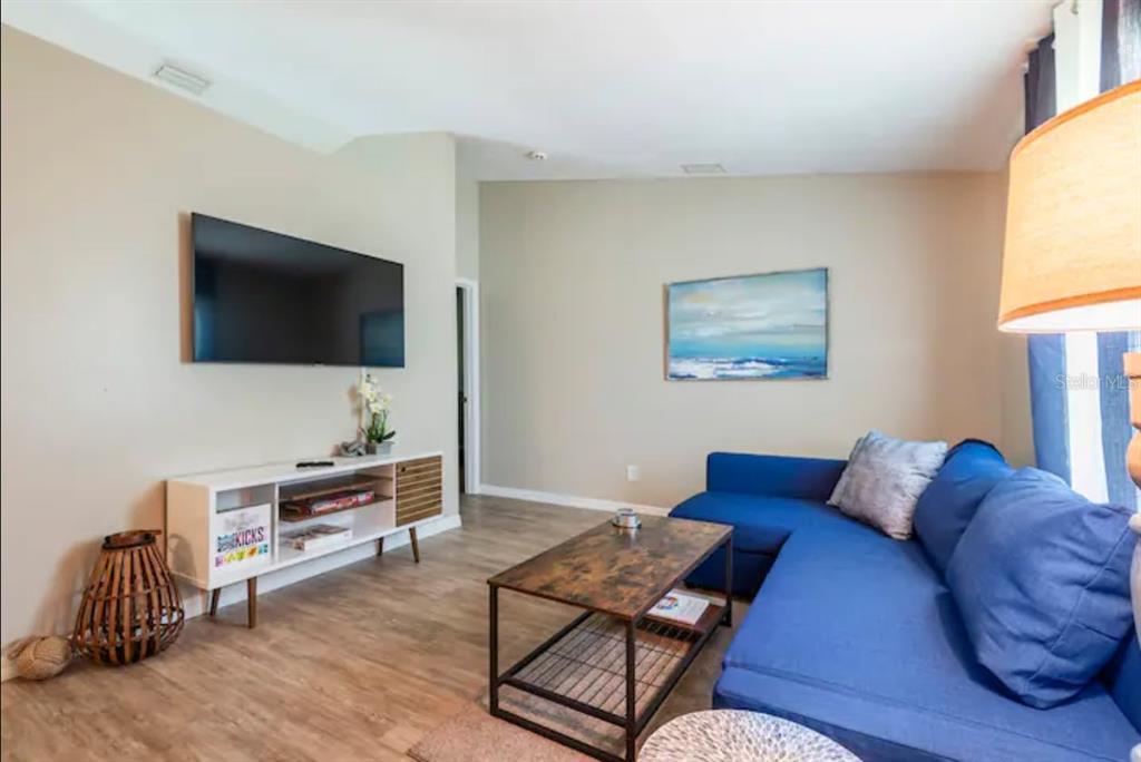 A living room features a blue sectional sofa, a wall-mounted television, and a coffee table — 2471 QUINCY AVENUE SE, PALM BAY, FL