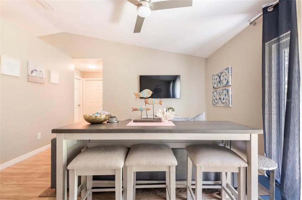 A dining table with three stools sits in front of a sofa and television — 2471 QUINCY AVENUE SE, PALM BAY, FL