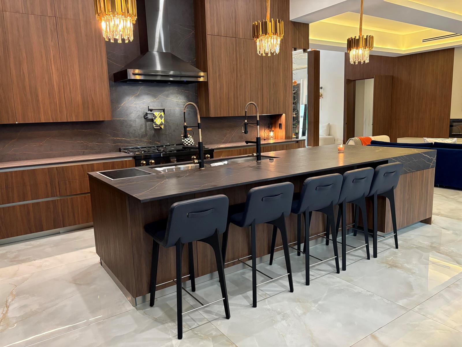 A modern kitchen features wood cabinetry, a large dark stone island, and gold pendant lights — 6935 Long Leaf Drive, Parkland FL 33076, PARKLAND, FL