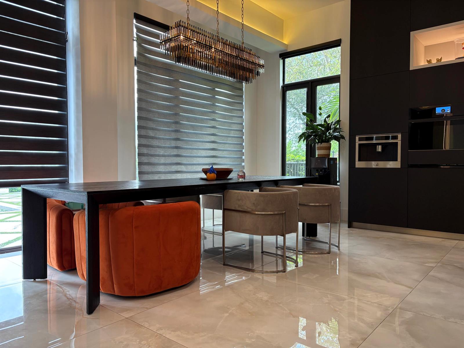 A modern dining room features a long black table, orange and beige chairs, and a chandelier — 6935 Long Leaf Drive, Parkland FL 33076, PARKLAND, FL