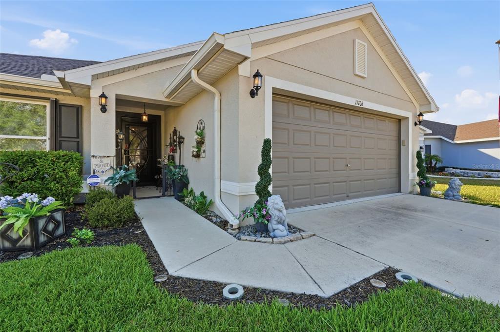 A tan single-story house features a two-car garage, a covered entryway, and landscaped front yard — 11706 SUNDER BERRY STREET, HUDSON, FL