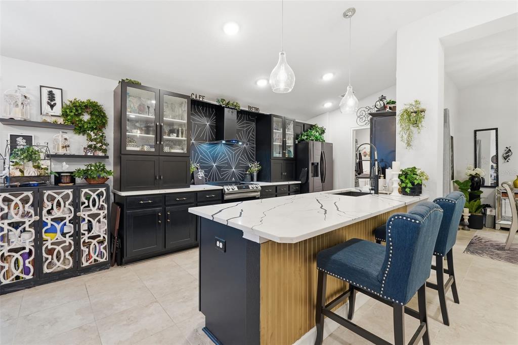 A modern kitchen features black cabinetry, a white marble island, and a geometric backsplash — 11706 SUNDER BERRY STREET, HUDSON, FL