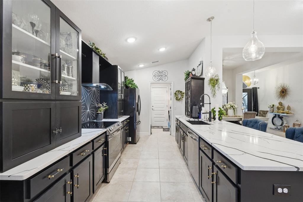 A modern kitchen features black cabinetry, white marble countertops, and a central island — 11706 SUNDER BERRY STREET, HUDSON, FL