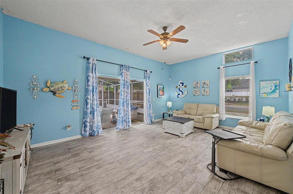 A living room with light blue walls, tile flooring, two sofas, and a ceiling fan — 655 SAND RIDGE DRIVE, VALRICO, FL