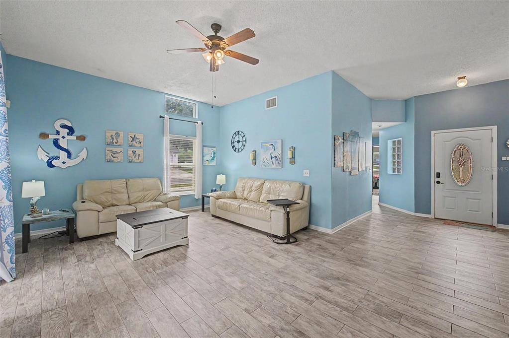 A living room features light blue walls, light wood-look tile flooring, and two beige sofas — 655 SAND RIDGE DRIVE, VALRICO, FL