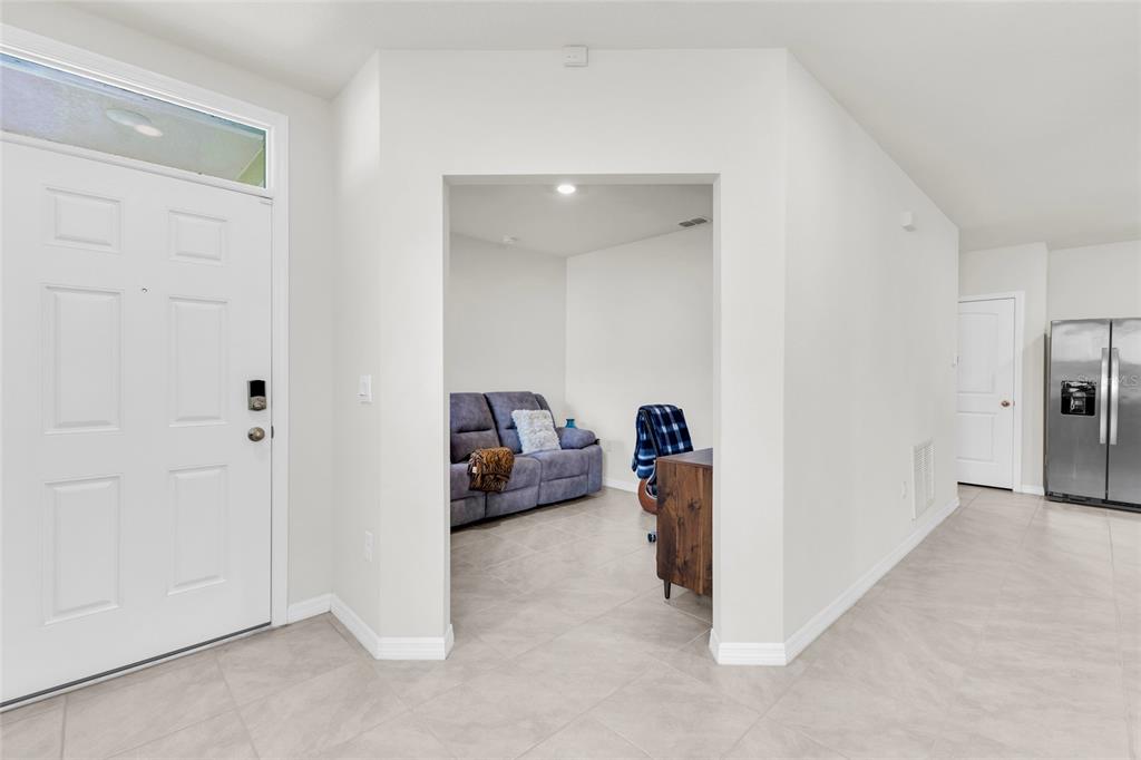 A view from an entryway looking into a living area with tile floors and furniture — 20010 ROYAL TERN COURT, LEESBURG, FL