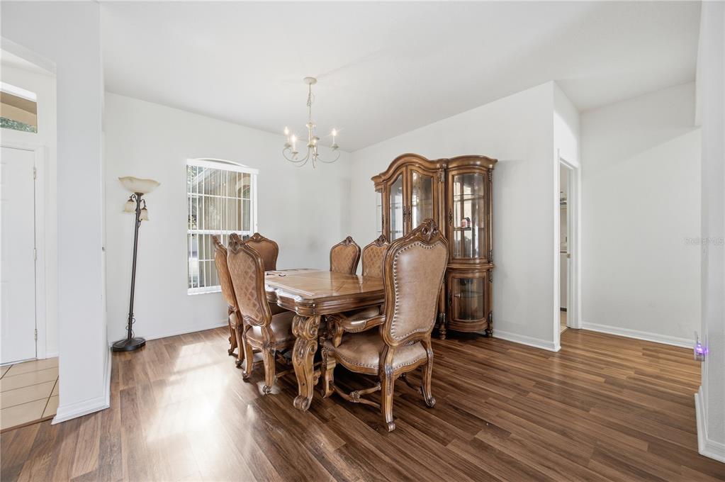 A dining room features wood-look flooring, a traditional wooden dining set, and a matching china cabinet — 3905 BOWFIN TRAIL, KISSIMMEE, FL