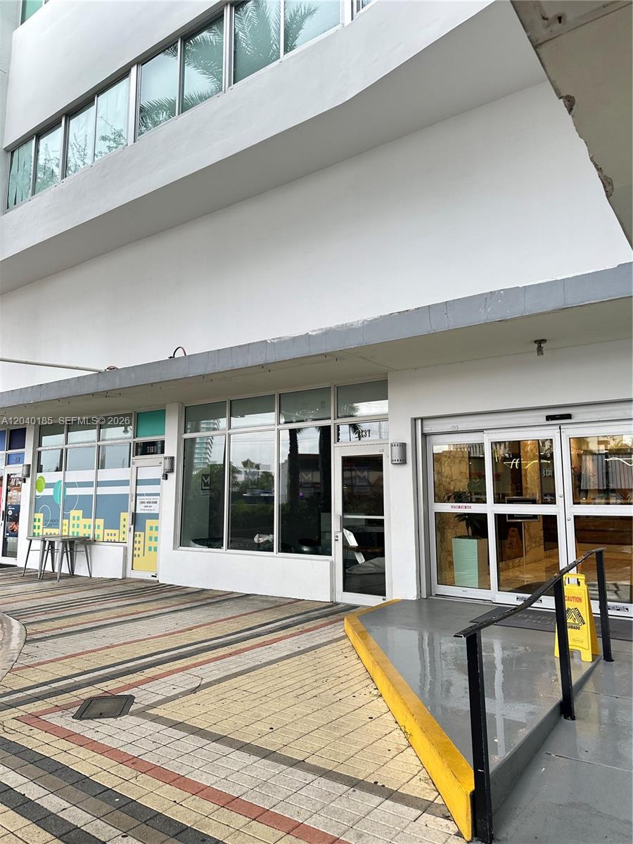 The exterior of a commercial building features glass storefronts, a ramp, and a paved walkway — 7135 Collins Ave # 1523, Miami Beach FL 33141, MIAMI BEACH, FL