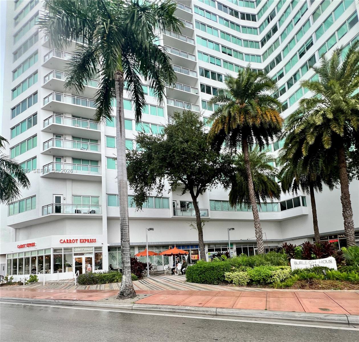 A multi-story white residential building features a ground-floor Carrot Express restaurant and palm trees — 7135 Collins Ave # 1523, Miami Beach FL 33141, MIAMI BEACH, FL