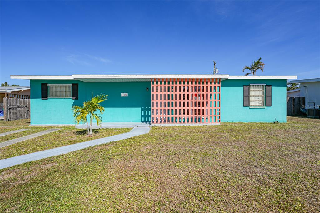A single-story teal house features a decorative orange breeze block screen and a concrete walkway — 21470 EDGEWATER DRIVE, PORT CHARLOTTE, FL