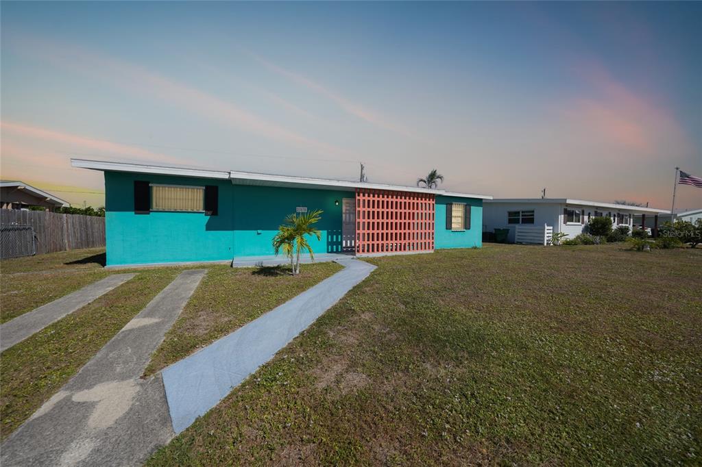 A turquoise single-story house features a decorative orange breeze block wall and a concrete walkway — 21470 EDGEWATER DRIVE, PORT CHARLOTTE, FL