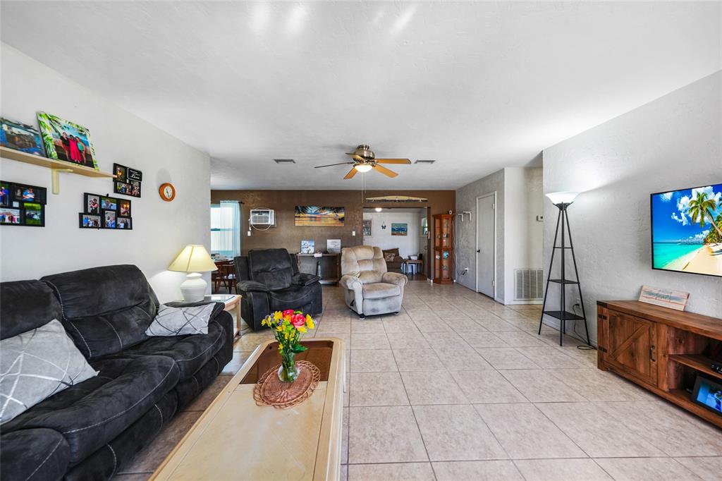 A living room features tile flooring, a ceiling fan, a television, and neutral walls — 21470 EDGEWATER DRIVE, PORT CHARLOTTE, FL