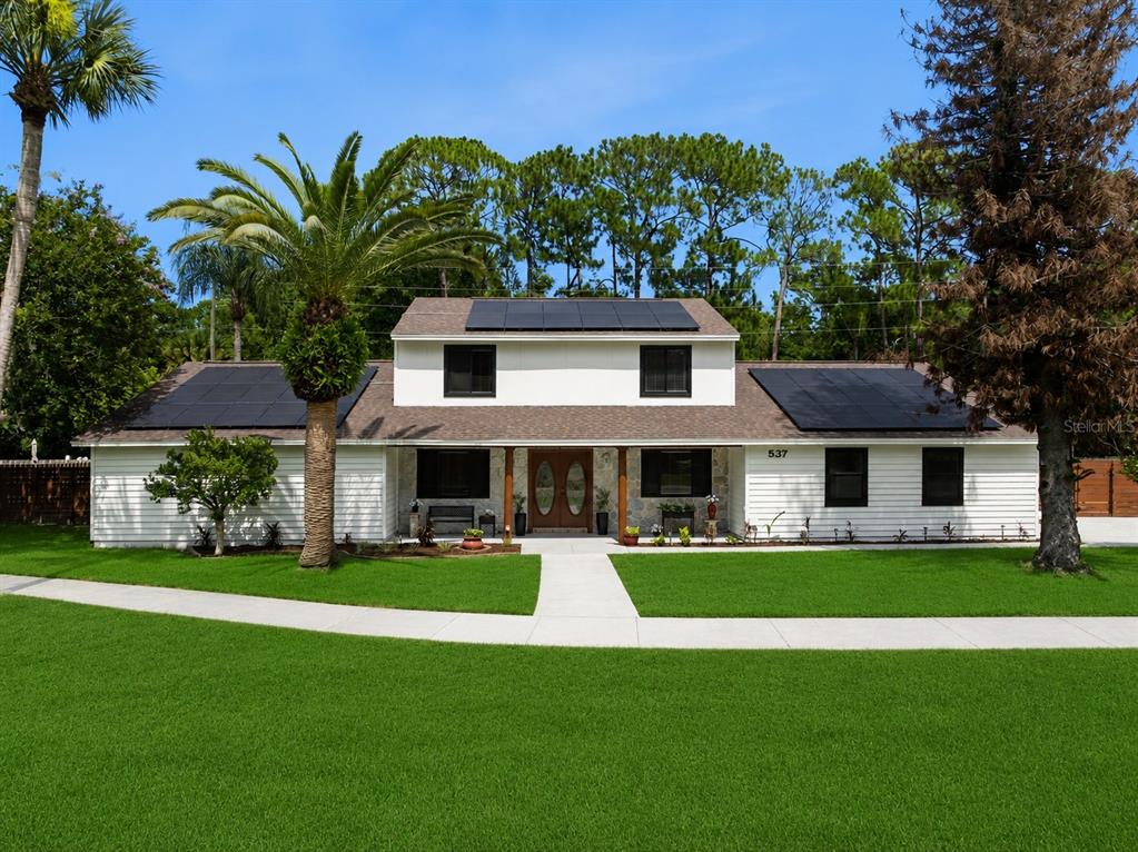 A two-story white house with solar panels on the roof and a palm tree — 537 PELICAN BAY DRIVE, DAYTONA BEACH, FL