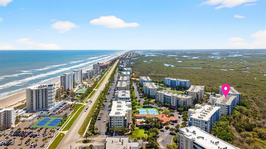 An aerial view shows coastal apartment buildings, a highway, and a marshy landscape — 5300 S ATLANTIC AVENUE UNIT 9-204, NEW SMYRNA BEACH, FL