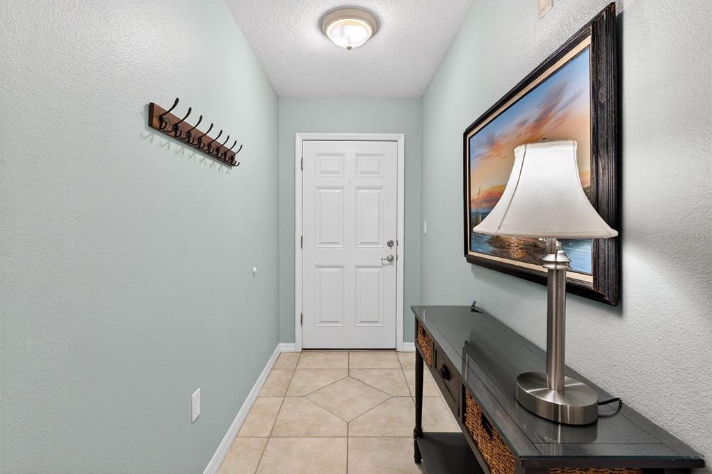 An entryway features light blue walls, tile flooring, a coat rack, and a console table — 5300 S ATLANTIC AVENUE UNIT 9-204, NEW SMYRNA BEACH, FL