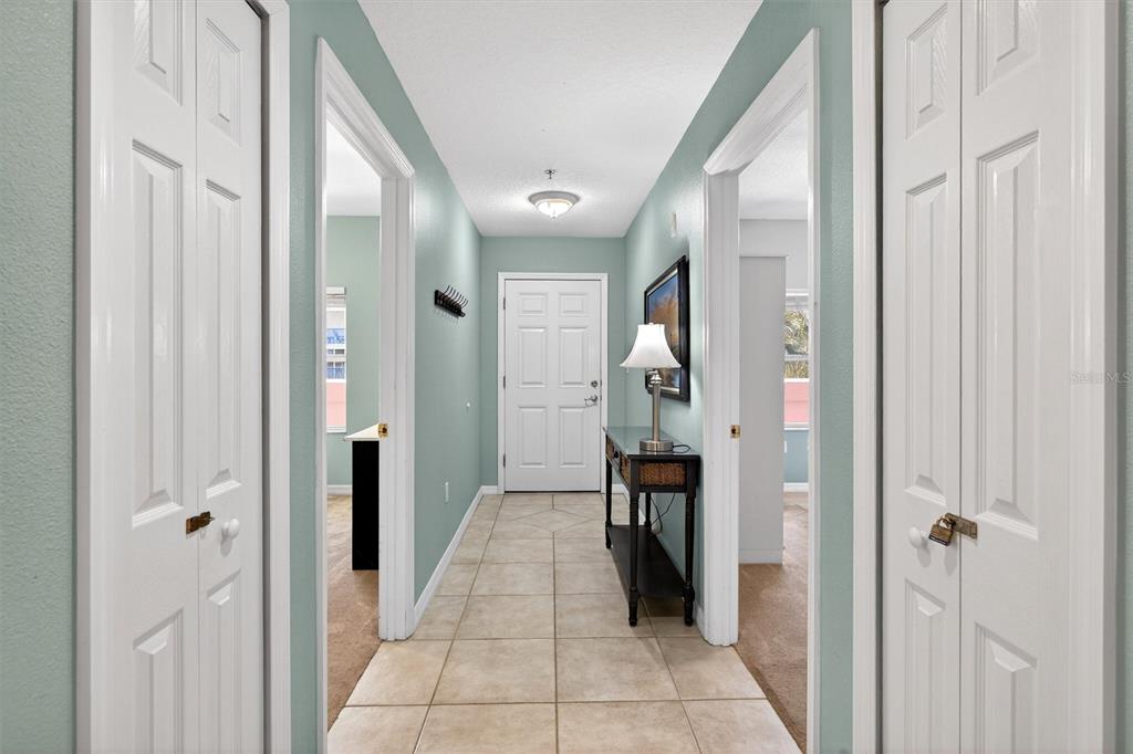 A tiled hallway leads to a white front door flanked by two doorways and closets — 5300 S ATLANTIC AVENUE UNIT 9-204, NEW SMYRNA BEACH, FL