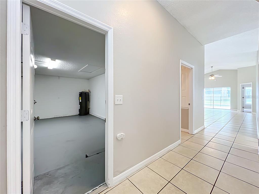 A tiled hallway leads to an open living area, with a garage entrance on the left — 1005 WINDING WATER WAY, CLERMONT, FL
