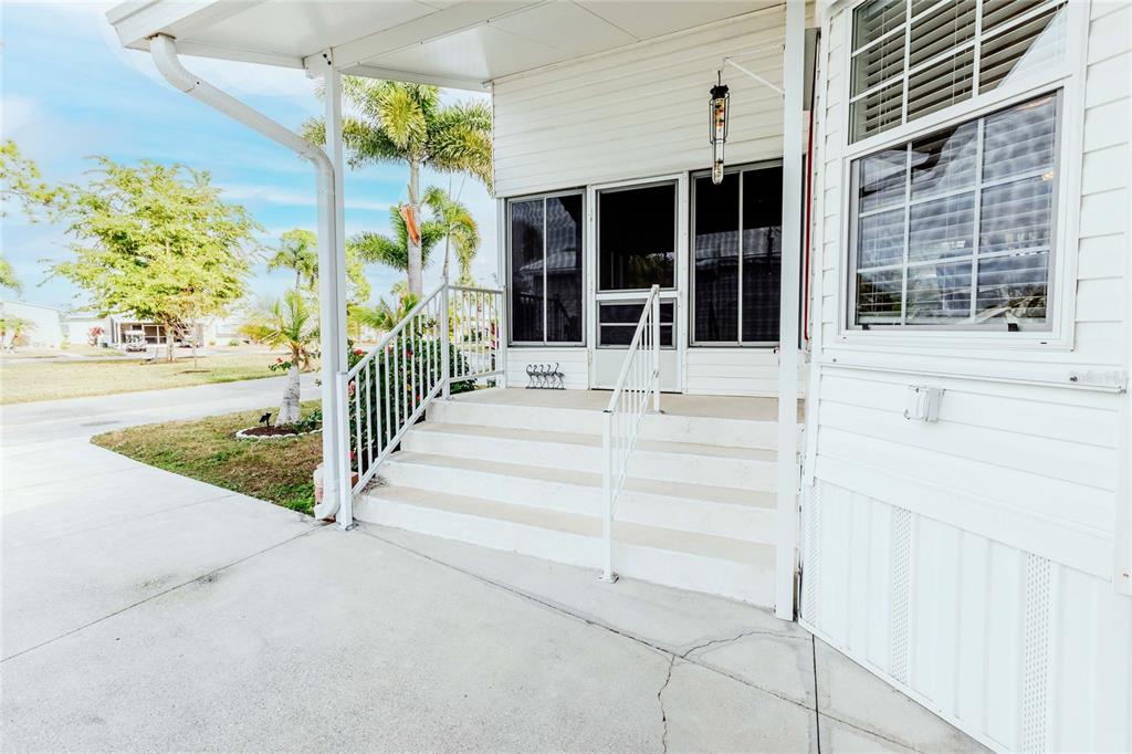 A white mobile home exterior features a concrete driveway, a covered porch, and stairs — 2100 KINGS HIGHWAY UNIT 1006, PORT CHARLOTTE, FL