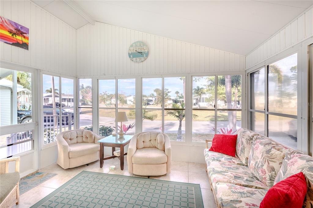 A sunroom with a vaulted ceiling, tile floors, two armchairs, and a floral sofa — 2100 KINGS HIGHWAY UNIT 1006, PORT CHARLOTTE, FL