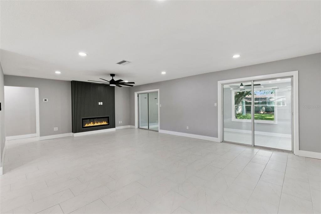 A living room with light tile floors, gray walls, and a black slatted fireplace feature wall — 10633 WATERTOWN COURT, ORLANDO, FL