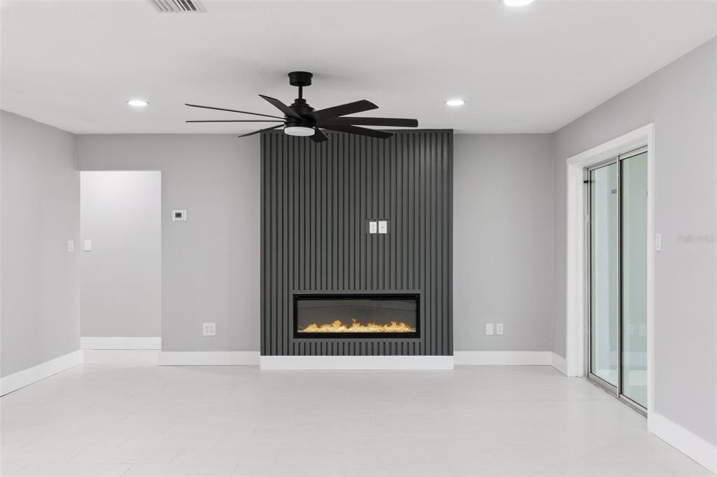 A living room features a dark gray slatted accent wall with a built-in electric fireplace — 10633 WATERTOWN COURT, ORLANDO, FL