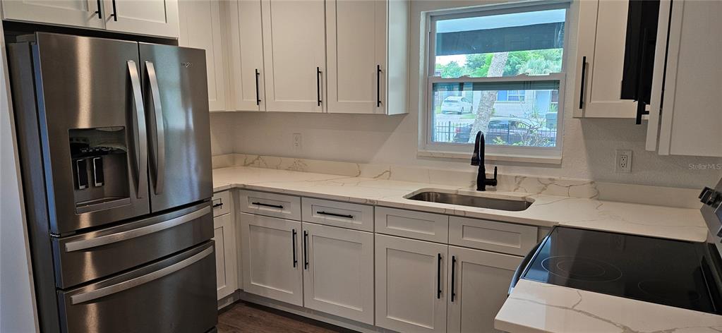 A kitchen features white cabinets, stainless steel appliances, and white marble-patterned countertops — 1304 HILLCREST DRIVE, DAYTONA BEACH, FL