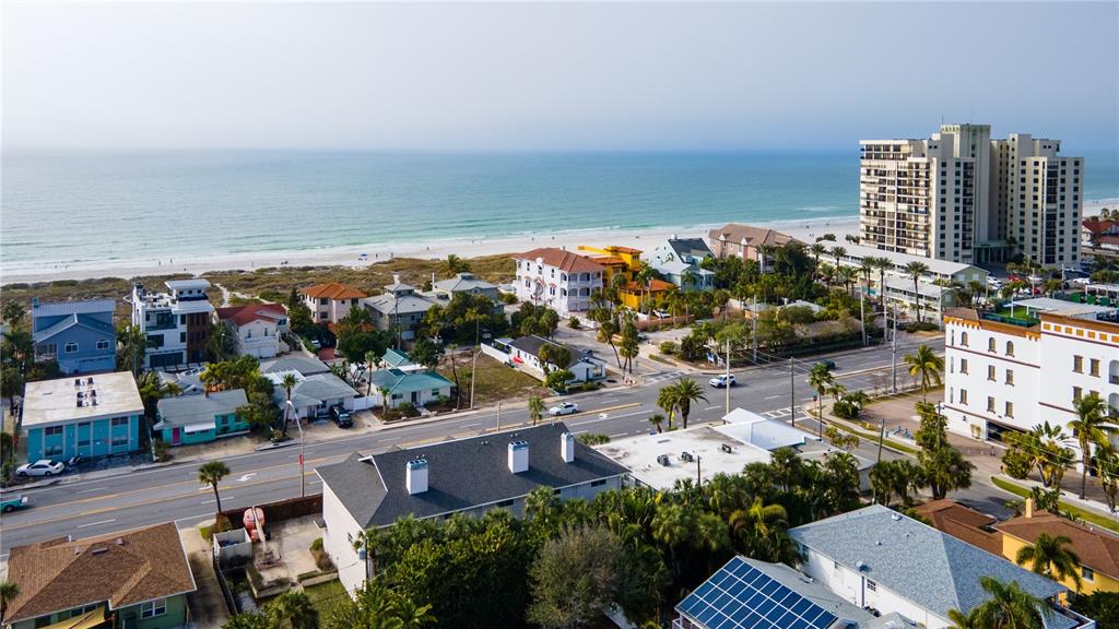 An aerial view shows a vacant lot situated between two residential buildings near a road — 3614 GULF BOULEVARD, ST PETE BEACH, FL