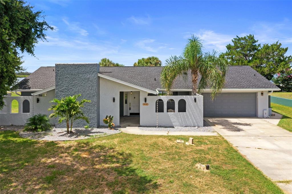 A single-story house with a gray textured chimney, arched wall cutouts, and a two-car garage — 11930 W BAYSHORE DRIVE, CRYSTAL RIVER, FL