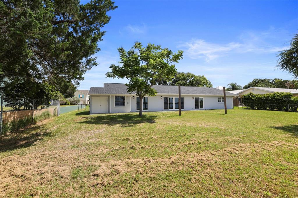 The exterior view shows the back of a single-story house with a large grassy yard — 11930 W BAYSHORE DRIVE, CRYSTAL RIVER, FL