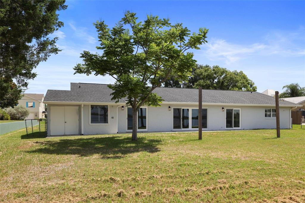 The exterior of a light-colored, single-story house features a large tree and a grassy yard — 11930 W BAYSHORE DRIVE, CRYSTAL RIVER, FL