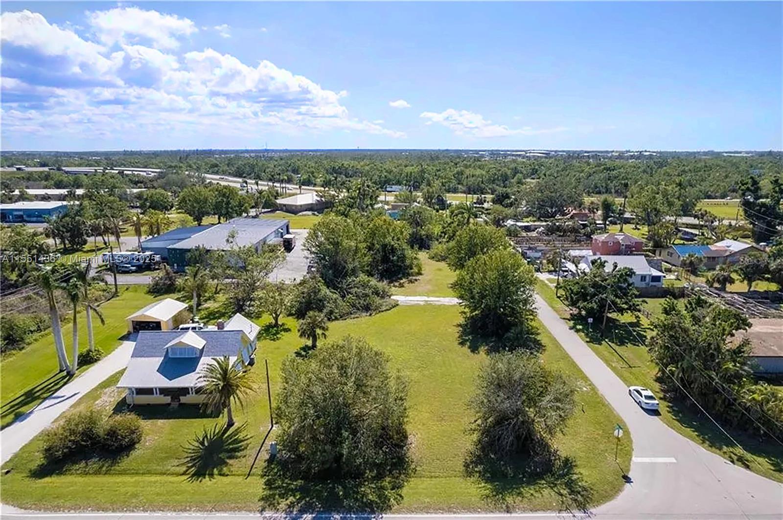 An aerial view shows a grassy vacant lot situated between a house and a road — 514 SOLANA LOOP, Punta Gorda FL 33950, PUNTA GORDA, FL
