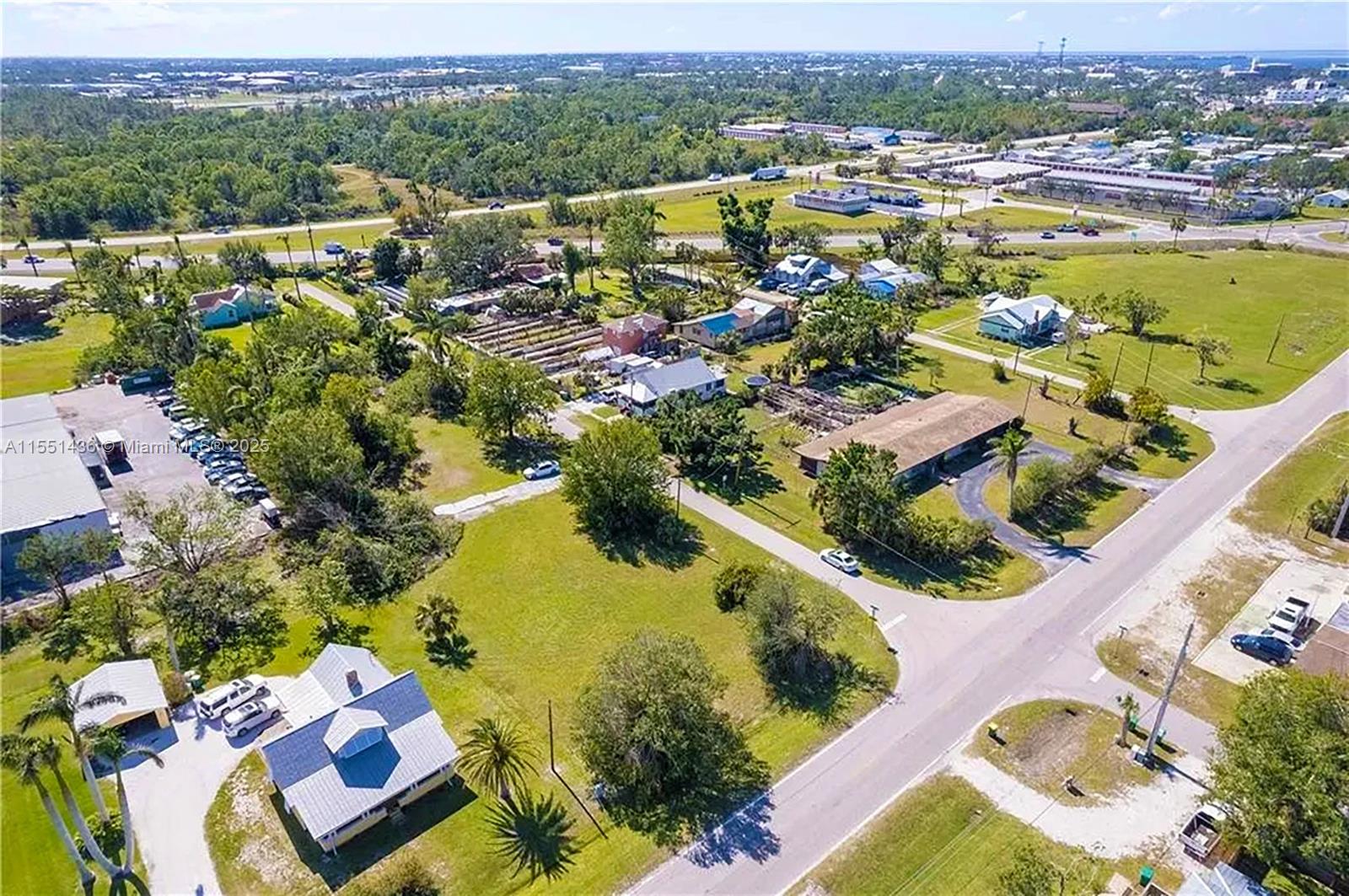 An aerial view shows several houses, a parking lot, and roads surrounded by green vegetation — 514 SOLANA LOOP, Punta Gorda FL 33950, PUNTA GORDA, FL