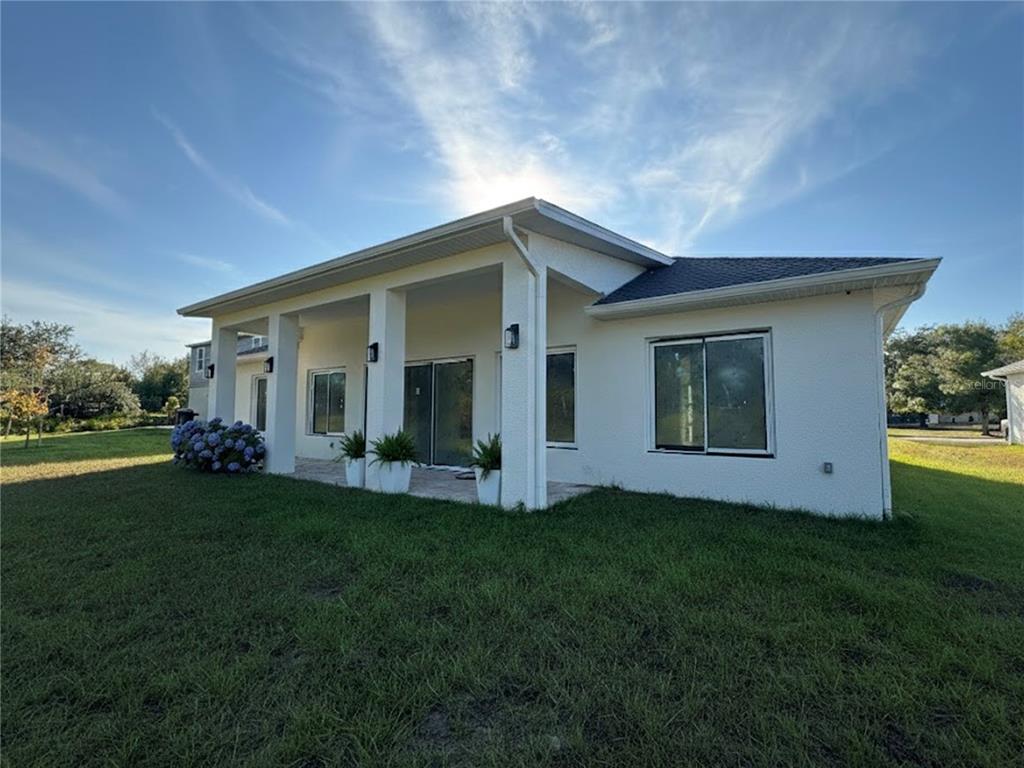 A white stucco house with a covered patio and large windows under a blue sky — 23372 ROSEWOOD AVENUE, PUNTA GORDA, FL