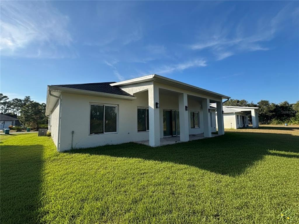 The exterior view shows the back of a white house with a covered patio area — 23372 ROSEWOOD AVENUE, PUNTA GORDA, FL