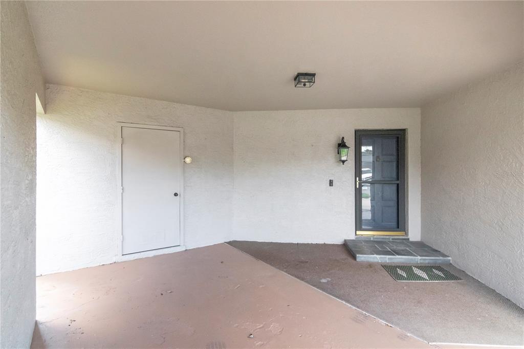A covered entryway features a white door, a dark door with glass, and concrete flooring — 2655 BARKSDALE COURT, CLEARWATER, FL