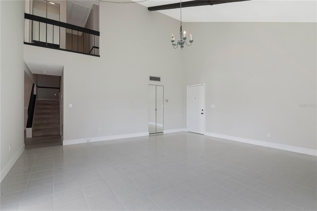 A spacious living room features high ceilings, a chandelier, tiled floors, and a lofted balcony — 2655 BARKSDALE COURT, CLEARWATER, FL